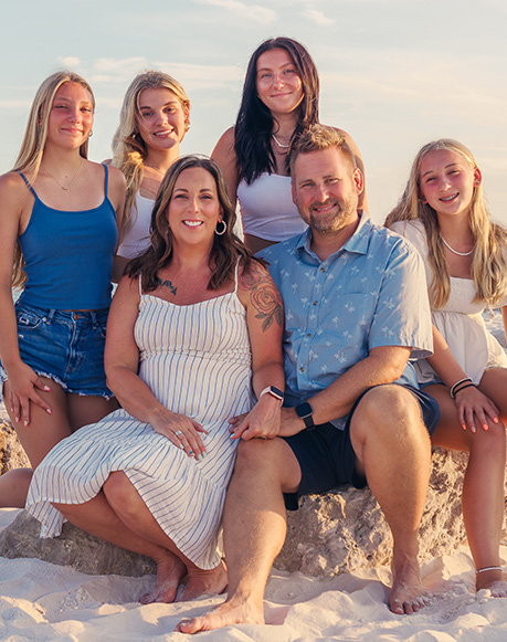 Photo taken of a family on the beach at sunset wearing whites and blues. Family photographer in orange beach, Alabama. Professional photographer in Orange Beach Alabama.