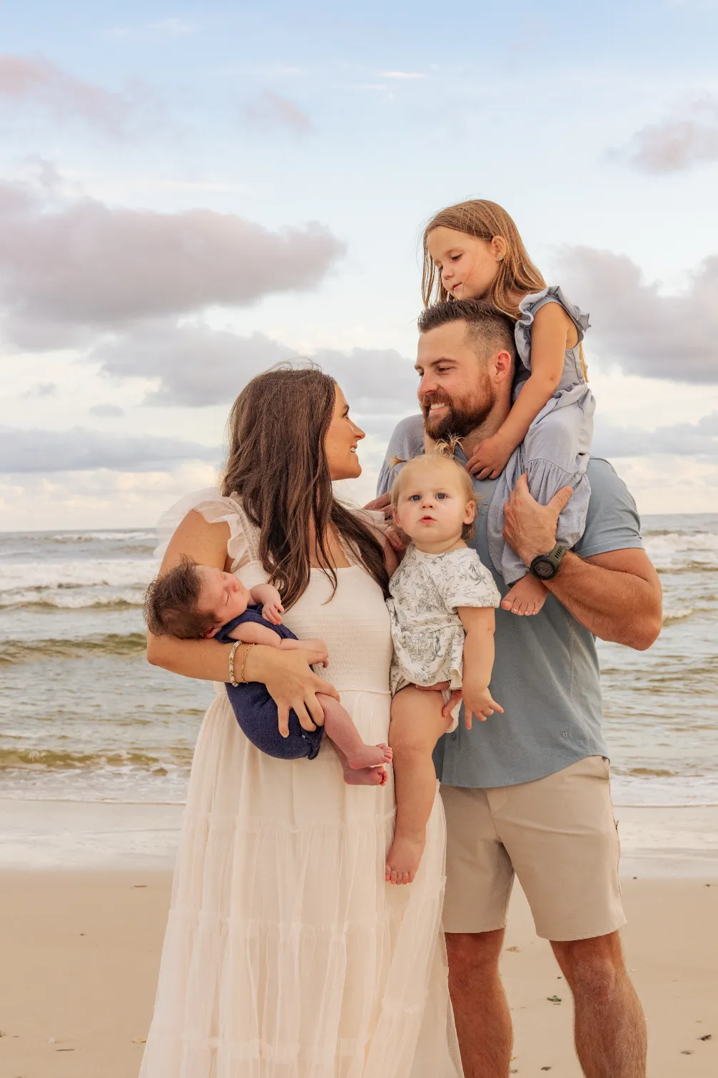 A small family with three kids taking a candid beach photo during a Gulf Shores family beach photoshoot.