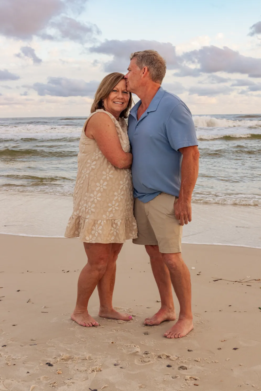 A candid photo of a grandfather kissing his wife on the beach during a Gulf Shores family beach photoshoot..