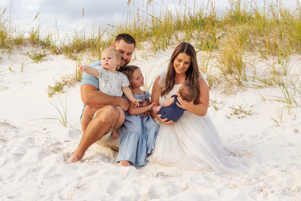 A candid shot of a small family sitting on the beach during a Gulf Shores family beach photoshoot.