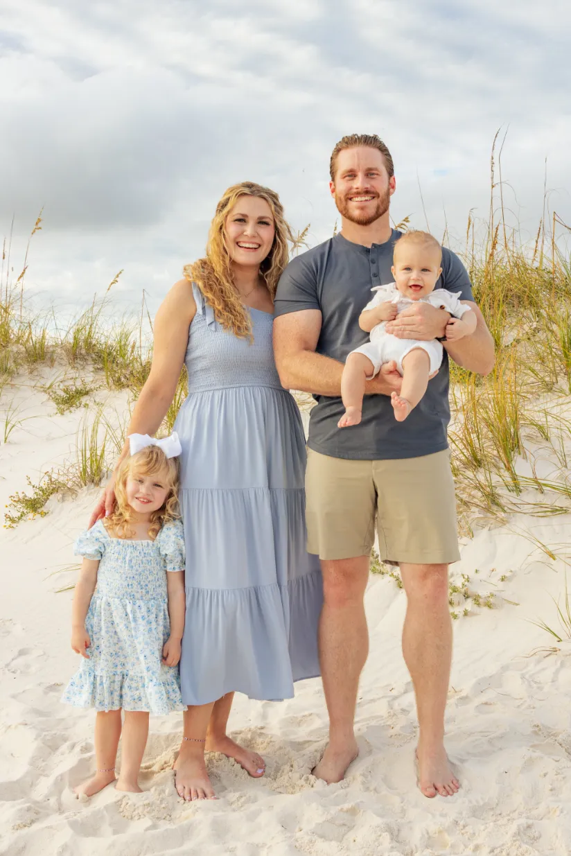 Posed photo of a small family with kids standing on the beach during a Gulf Shores family beach photoshoot.