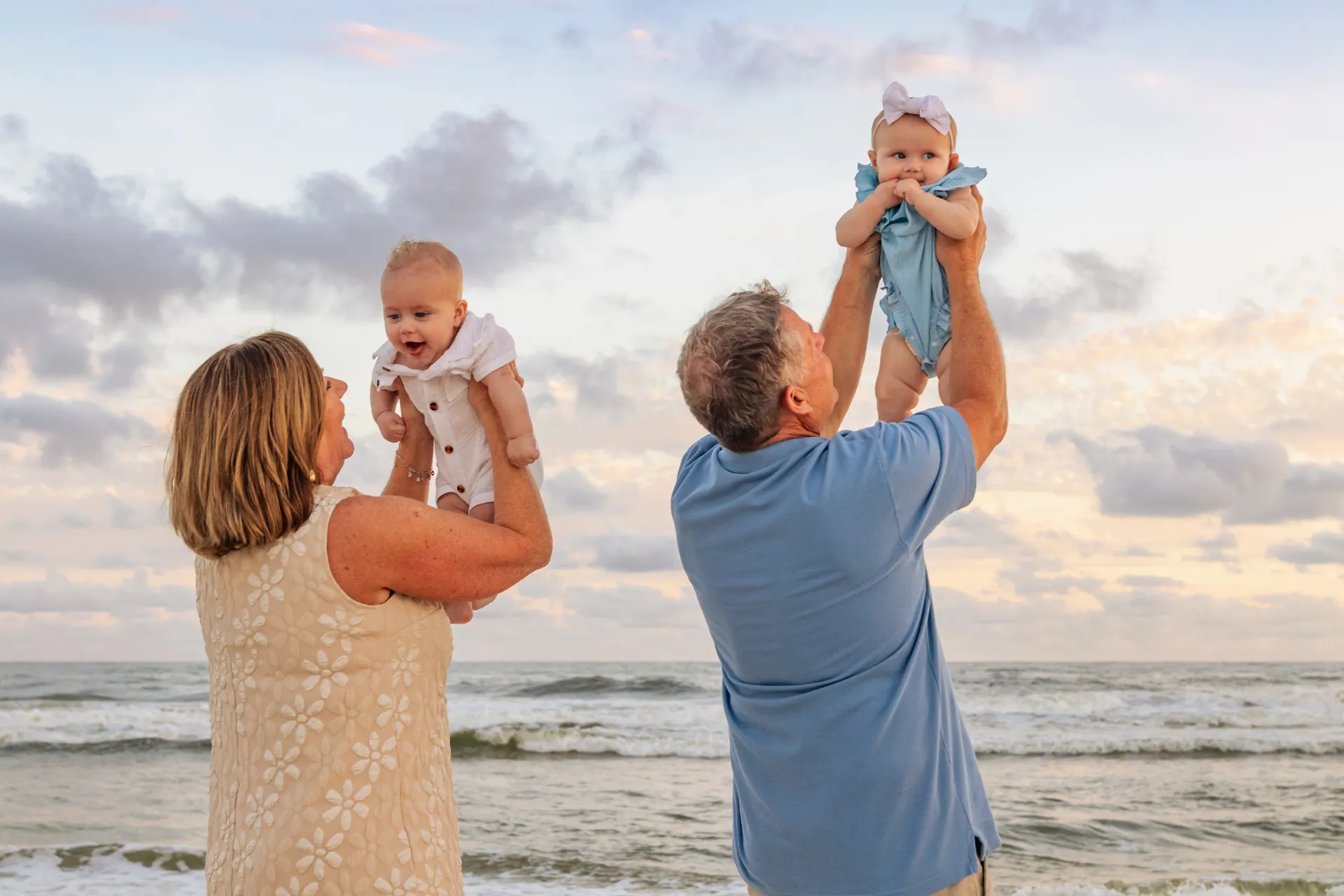 A photo of grandparents holding their grandkids up in the sky during a during a Gulf Shores family beach photoshoot.