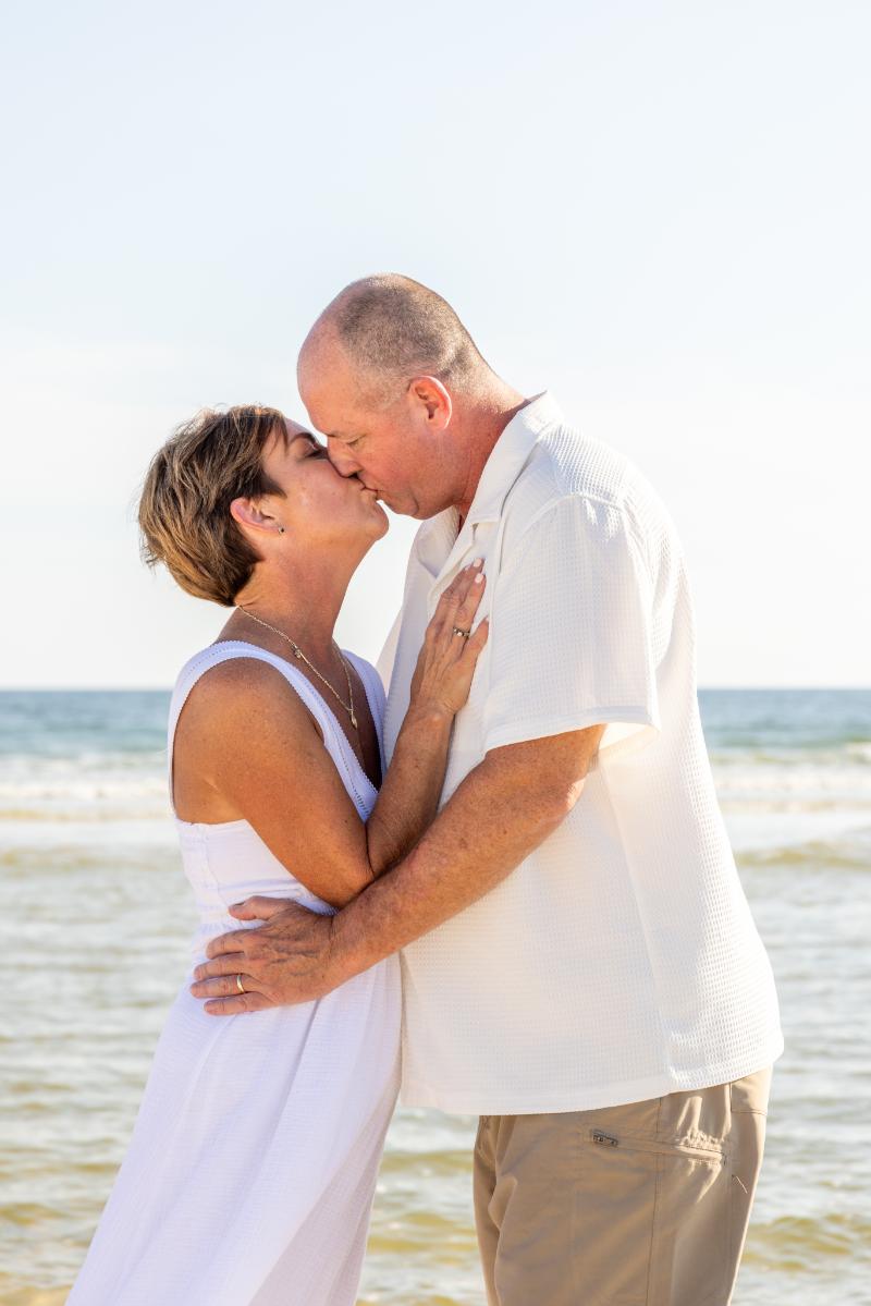 Anniversary photoshoot in Gulf Shores, Alabama. A man kissing his wife on the beach. Gulf Shores anniversary photographer